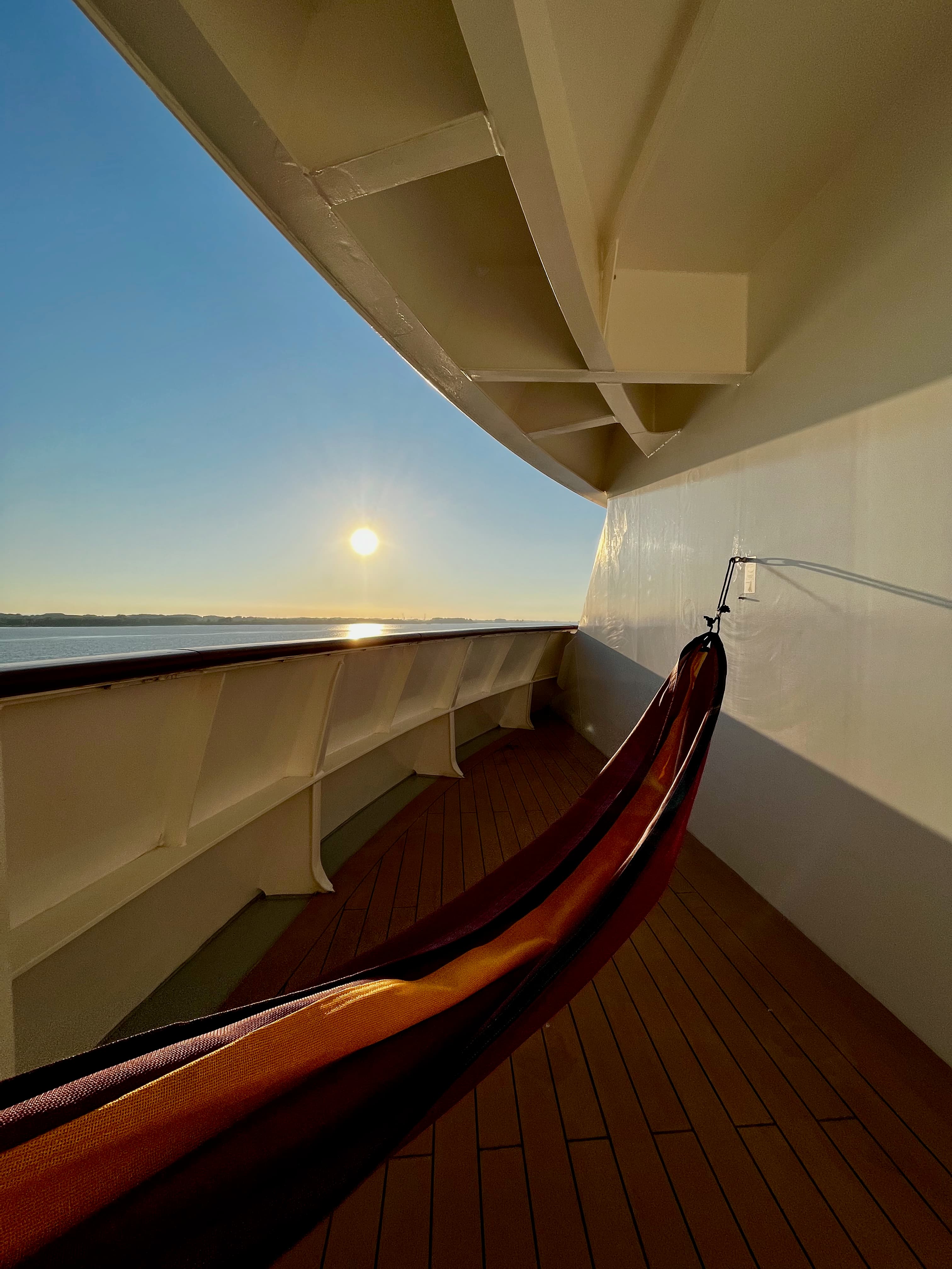 Eine Hängematte auf einem Balkon eines Schiffes im Sonnenuntergang